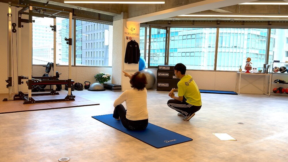 a physiotherapist is catting with his elderly client in a rehabilitation gym.