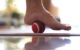 a women is releasing tension of her sole muscles by using a tennis ball to treat her plantar fasciitis.