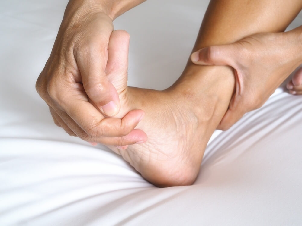 a man who is struggling with his plantar fasciitis on L sole is stretching his foot.