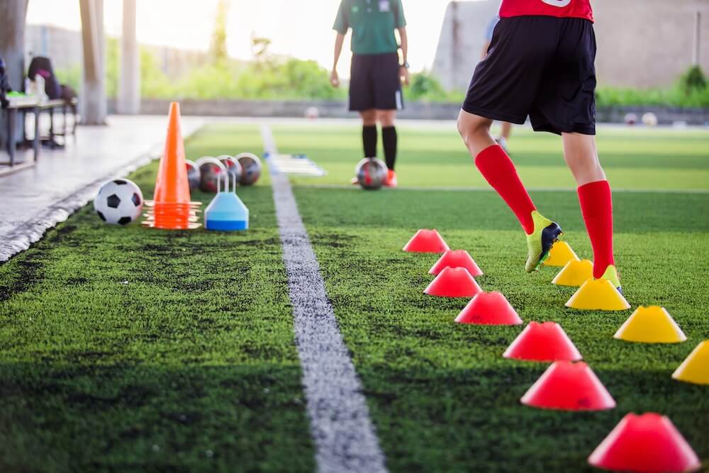 a football player is doing sports specific rehabilitation with his physiotherapist on the football field