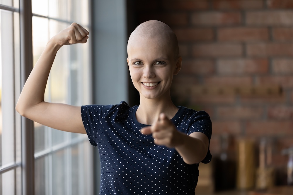 Portrait of young sick hairless woman struggle with cancer show strength power beating disease, happy ill female patient point at screen, feel optimistic strong battling oncology, healthcare concept